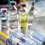 Vials of different size next to syringes at a hospital table, conceptual image